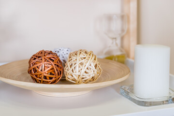 home decor concept. Wicker decorative balls on wooden plate. Interior composition with geometric shapes and white candle.Rattan dry decorative balls, natura decoration for Cozy home.