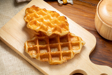 Waffles with butter and honey on a wooden tray ready to serve.