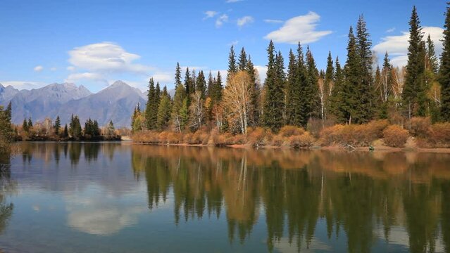 Beautiful autumn calm landscape with the Eastern Sayan Mountains and yellowed trees on the banks of the Irkut River. Baikal region, Buryatia, Tunka foothill  Valley