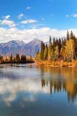 Obraz premium Autumn in highlands. View from river bank to mountain range and yellowed forest on bank of calm river. Baikal region, Buryatia, Eastern Sayan Mountains, Irkut River, Tunka valley, Nugan village