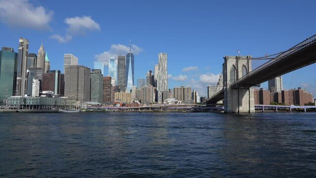 4K video filmed from a boat ferry cruise on East River with Manhattan and Brooklyn bridges landmark and other iconic buildings from New York City during a beautiful sunny day.