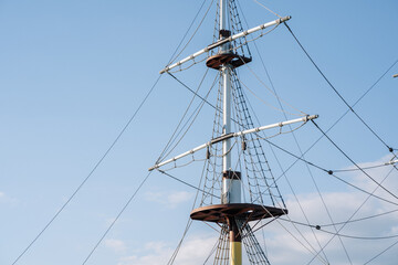 Fototapeta na wymiar mast and rigging of ship. top of the old sailing ship mast, yards and rigging against blue sky