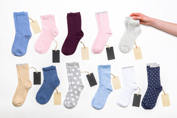 Female hand holding socks among women's cotton socks set with price tags on white background....