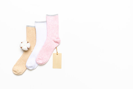 Various modern trendy women's cotton socks set with cotton flowers and price tags on white background. Fashionable socks store. Socks shopping, sale, merchandise, advertisement concept. Copy space