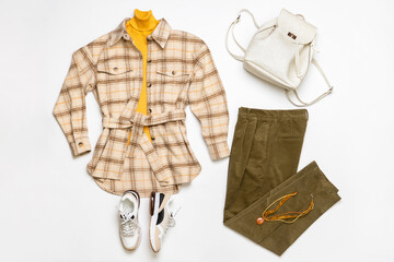 Female winter or autumn stylish clothing set. Plaid checkered shirt, yellow sweater, green corduroy trousers, sneakers and backpack. Trendy fashionable casual clothes. Fashion concept