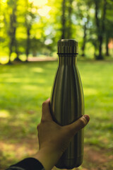 Close-up of Unrecognizable female hand holding Water bottle. Reusable steel thermo water bottle in...