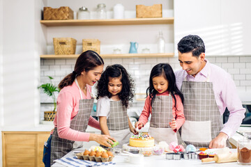 Portrait of enjoy happy love asian family father and mother with little asian girl daughter child play and having fun cooking food together with baking cookie and cake ingredient in kitchen