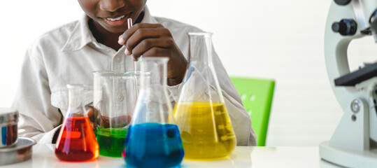 African american cute little boy student child learn science research and doing a chemical science experiment making analyzing and mix liquid in test tube on class at school