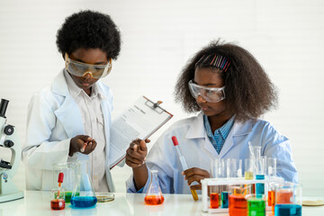 Two african american cute little boy and girl student child learn science research and doing a...