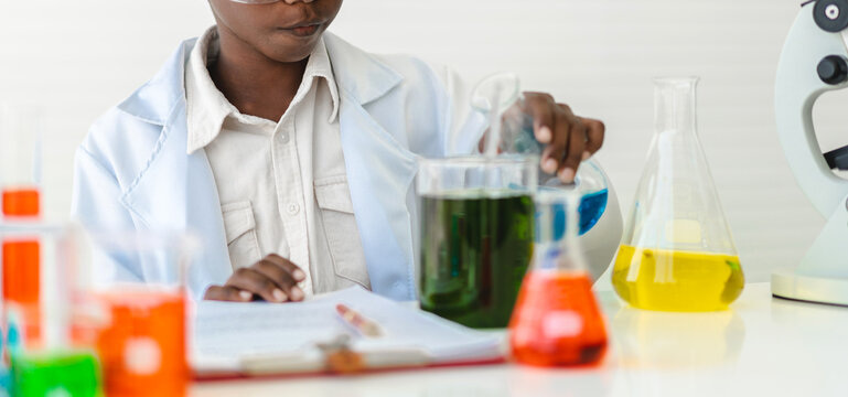 African american cute little boy student child learn science research and doing a chemical science experiment making analyzing and mix liquid in test tube on class at school