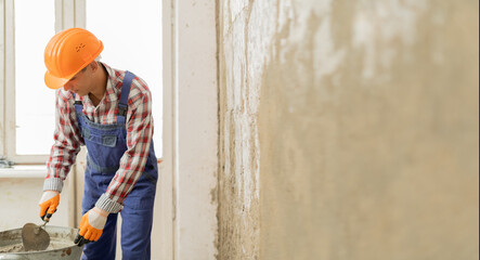 builder worker plasterer holding and using trowel to plastering cement wall in home. building...