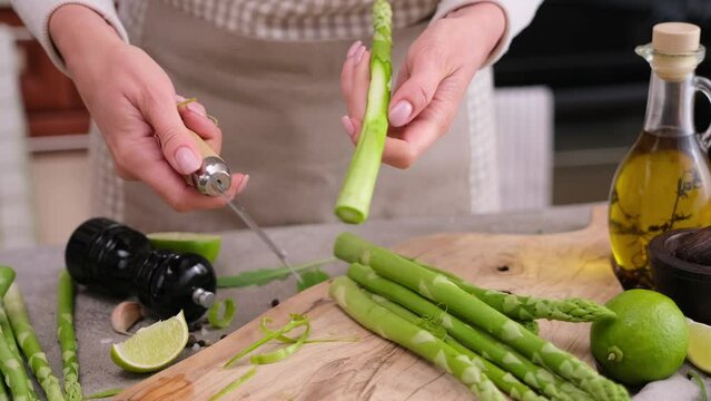Woman peeling Fresh green organic natural asparagus at domestic kitchen