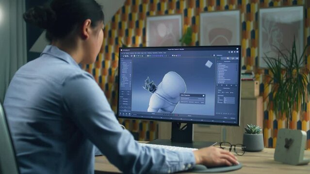Female 3D designer creating and drawing character for video game using computer while sitting at the table at home office and doing distant work. 3D modeling