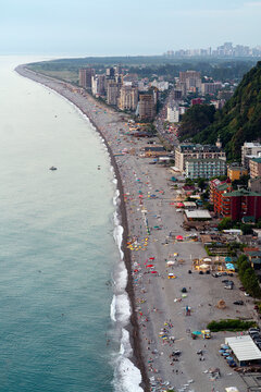 Top view on a sunny day on the coast of a seaside resort in the high tourist season. People relax and sunbathe on the beach in Kvariati and Gonio in Adjara.