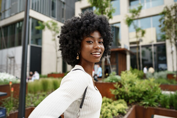 Portrait of young african woman with afro hairstyle smiling in urban background