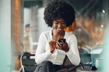 Portrait of a beautiful young african woman using her cellphone in a cafe