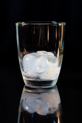 ice in whisky glass on a black table.