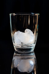 ice in whisky glass on a black table.