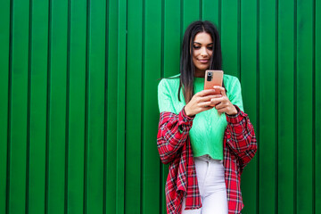 young hipster woman with phone on the wall