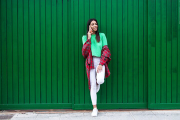 young hipster woman with phone on the wall