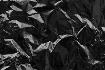 Shiny black foil texture background, pattern of wrapping paper with crumpled and wavy.