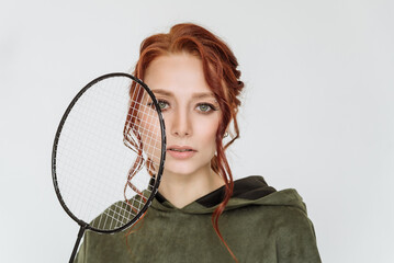 attractive young red-haired woman holding a tennis racket on a white background copy space. sports girl, tennis player