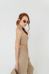portrait of a beautiful young redhead woman on a white background copy space. attractive caucasian woman in sunglasses with hairstyle and makeup.stylish fashion woman