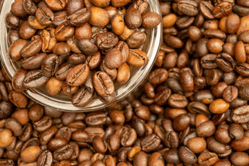 Roasted coffee beans scattered on the table and a small coffee cup.