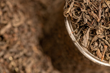 Large-leaf black tea in a glass and scattered on the table. Close-up of the surface texture