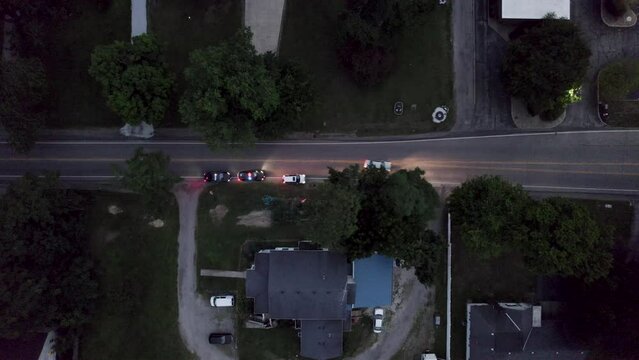An aerial shot of a cop car pulls over a speeding driver on the main road in the evening time