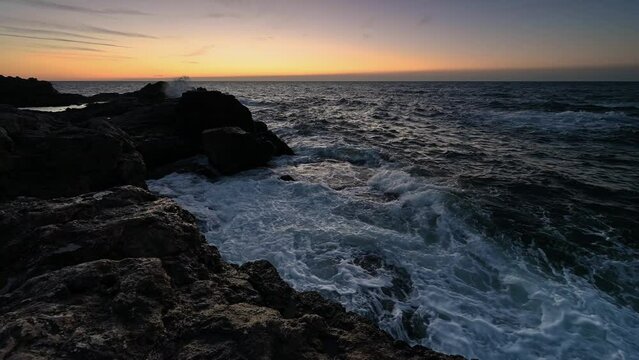 Amazing video with the sun rising, sea waves and a beautiful rocky coast.