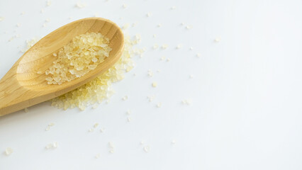 Fototapeta na wymiar Flavored yellow bath salt in wooden spoon on white background top view