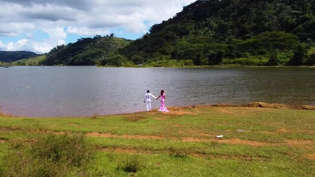 Drone shot of a couple holding hands on a lakeside