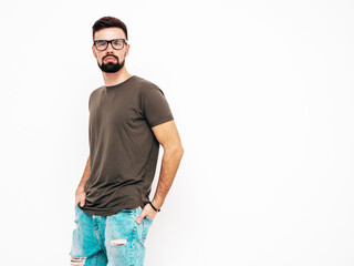 Fototapeta premium Portrait of handsome confident stylish hipster lambersexual model.Man dressed in T-shirt and jeans. Fashion male isolated on white wall in studio