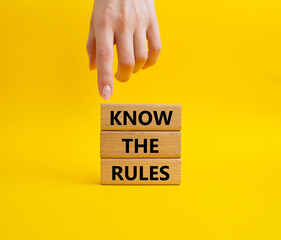 Know the rules symbol. Wooden blocks with words Know the rules. Beautiful yellow background. Businessman hand. Business and Know the rules concept. Copy space.