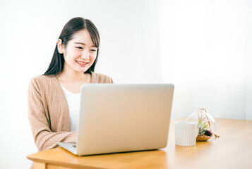 家でノートパソコンを使う女性（テレワーク）
