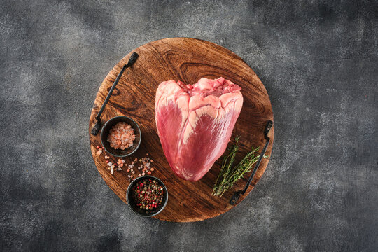 Top view closeup raw beef heart with spices.