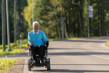 Smiling disabled old woman in a wheelchair on the highway