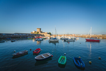 Fototapeta na wymiar Fort de Socoa at sunset, with port and small boats in foreground in Ciboure and Saint-Jean-de-Luz, France