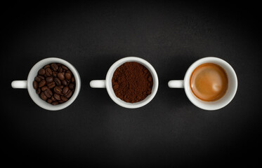 Three white cups with coffee on a black background. Coffee beans, ground coffee, black espresso...