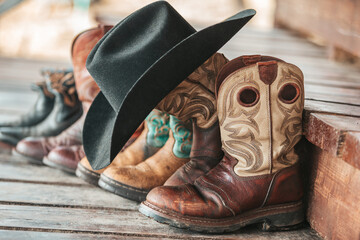 Western boots and black felt hat. Working cowboy boots on the background of brown wooden steps.