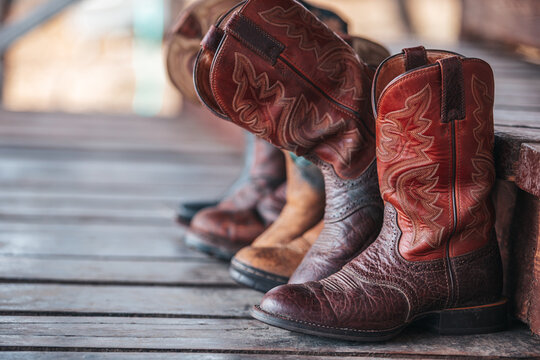Brown cowboy boots on wooden steps. Western shoes at the ranch.