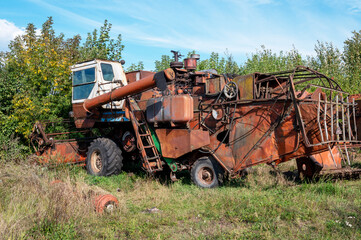 Old rusty agricultural machinery. Abandoned harvester, tractor