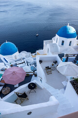 View from viewpoint of Oia village with blue domes of  greek orthodox Christian churches and traditional whitewashed greek architecture.  Santorini, Greece
