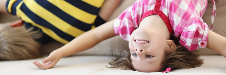 Children have fun at home, kids upside down on sofa, holiday at school