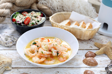 Shrimps in wine, butter and garlic, sprinkled with parsley. King prawns in a bowl, on white wood background.