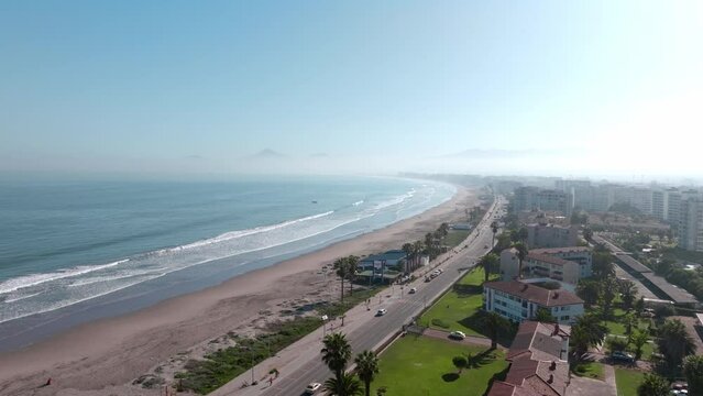 Aerial orbit of the waterfront of La Serena full of large houses with tile roofs and palm trees, Chile. Sunny day