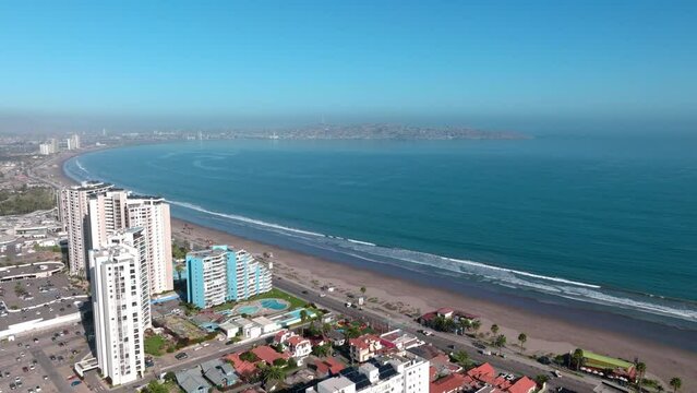 Dolly in aerial view of exclusive buildings and the waterfront of La Serena, Chile on a sunny day.