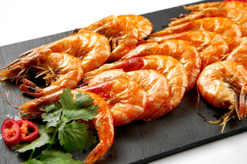 Roasted shrimp in spices on a black slate. White background, selective focus