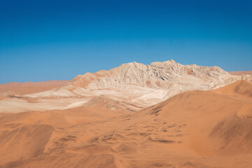 Fototapeta na wymiar mountain in between dunes with blue sky at sossuvlei national park in Namibia, stunning wallpaper